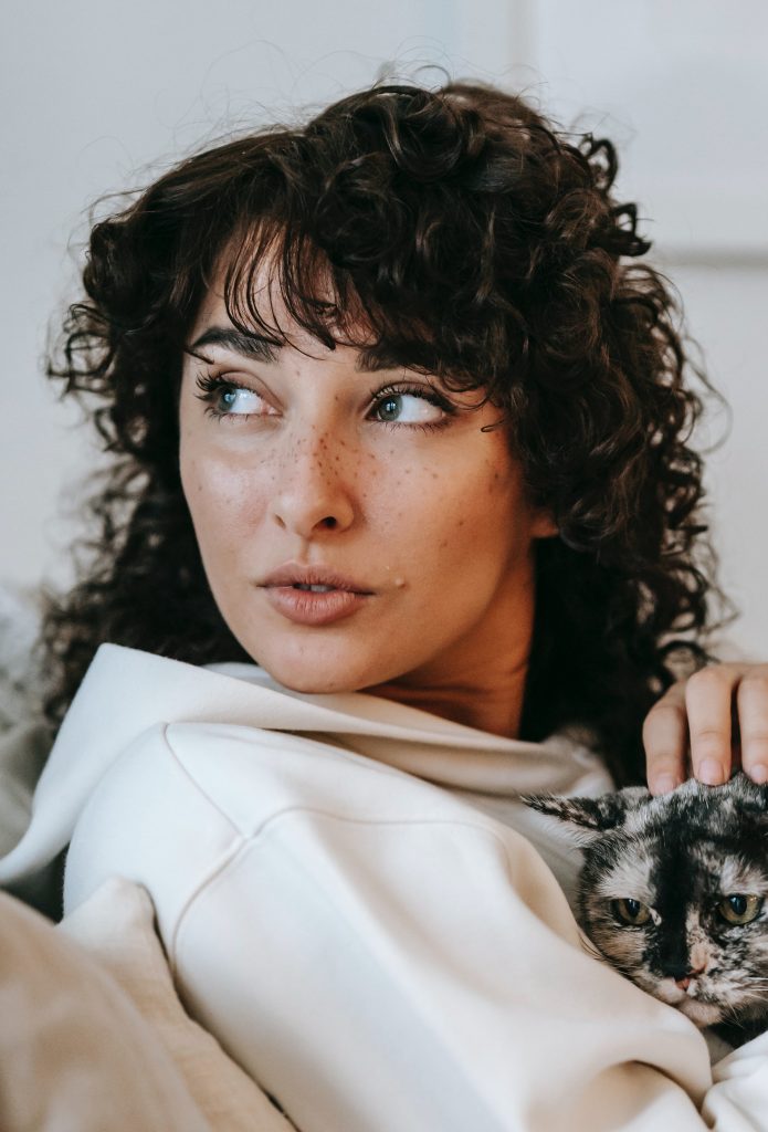 Woman at home with her cat, comfortable and glancing left.